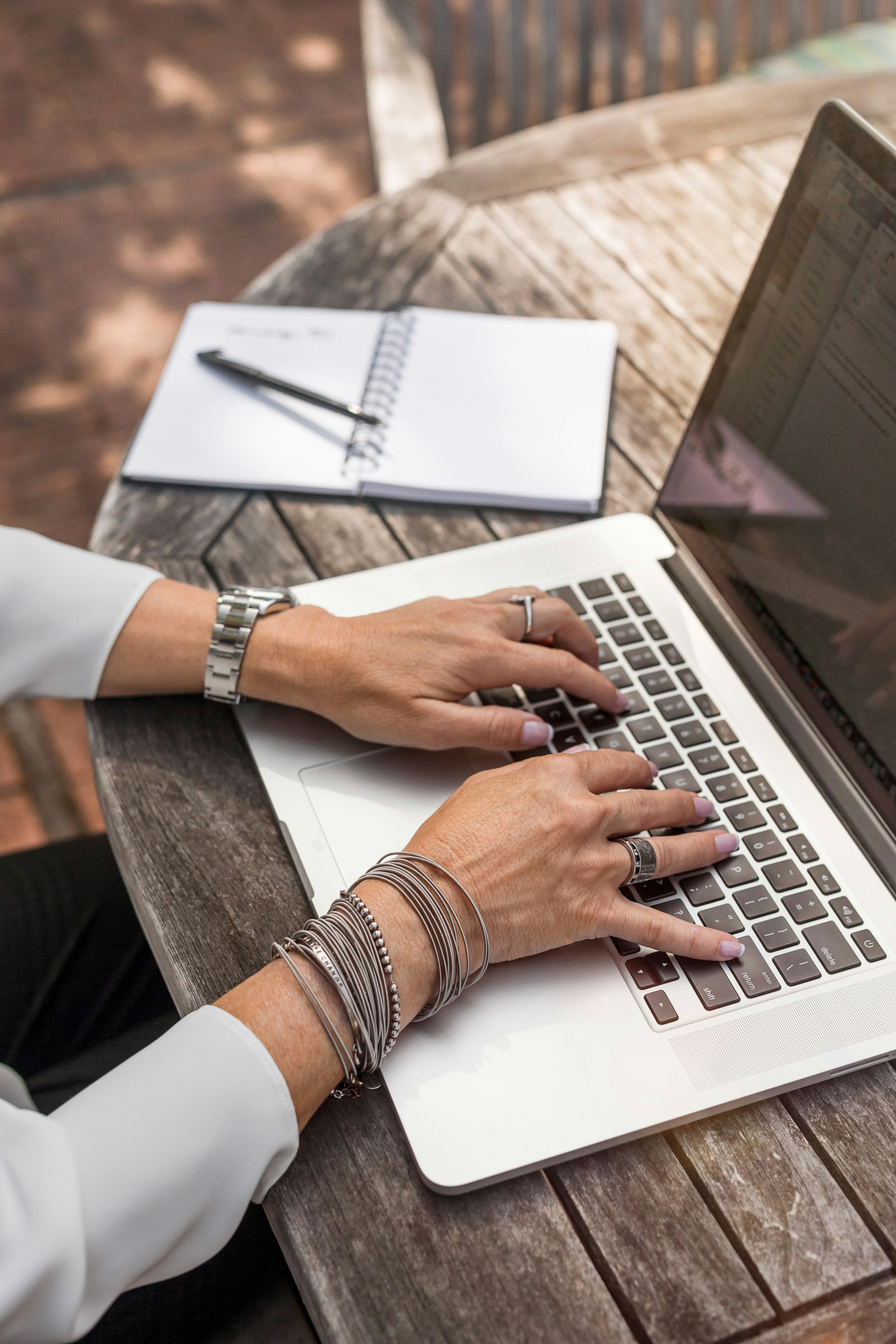 A laptop on a table showing women's hands typing on the PC.